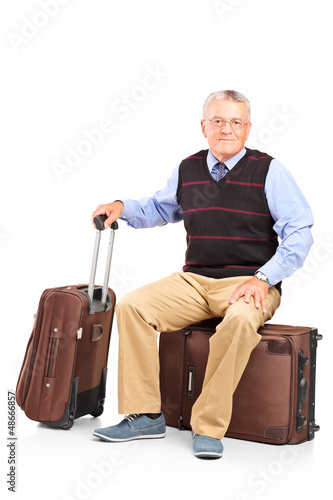 Photo: A mature man resting seated on a travel bag A mature man resting seated on a travel bag