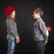 Lovely couple of kids. Boy offering flower on black background.