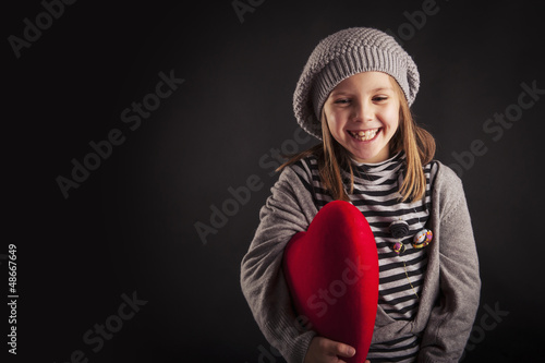 Photo: Lovely young girl with red heart on black background. Lovely young girl with red heart on black background.