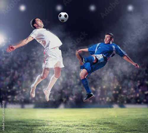 Photo: two football players striking the ball two football players striking the ball
