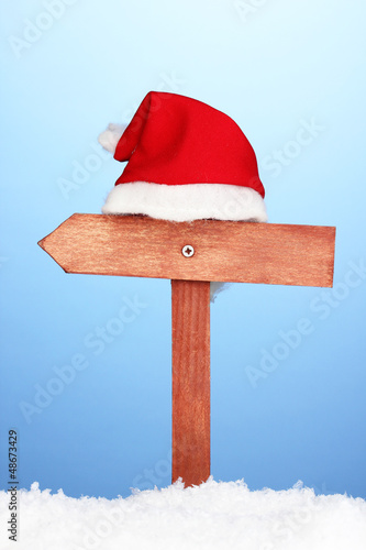 Photo: Wooden road sign with Santa hat on blue background Wooden road sign with Santa hat on blue background