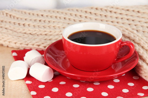 Photo: cup of coffee with scarf on table in room cup of coffee with scarf on table in room