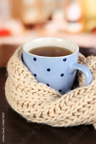 Photo: cup of tea with scarf on table in room cup of tea with scarf on table in room