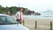Businessman talking on cell phone beside his car on a beach