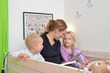 Mutter ließt Kindern im Bett eine Geschichte vor