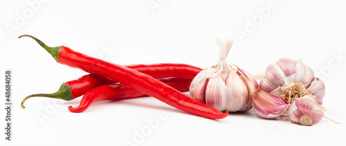 Photo: Red chilli peppers and garlic cloves on white background Red chilli peppers and garlic cloves on white background