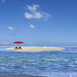 parasol rouge sur îlot de sable blanc