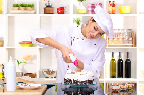 Photo: Young woman chef cooking cake in kitchen Young woman chef cooking cake in kitchen