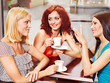 Women at laptop drinking coffee in a cafe.