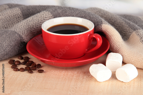 Photo: cup of coffee with scarf on table in room cup of coffee with scarf on table in room