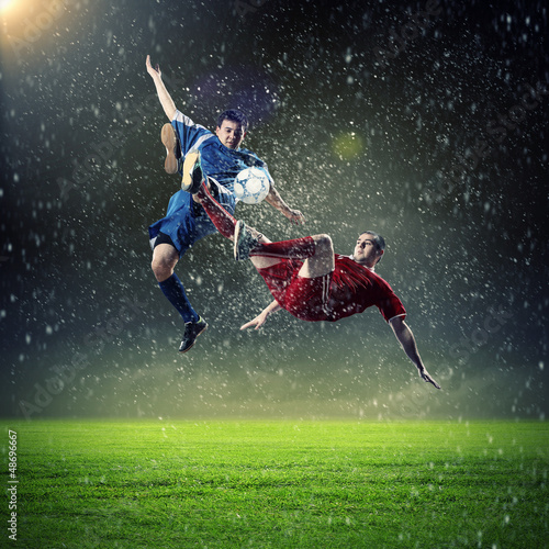 Photo: two football players striking the ball two football players striking the ball