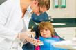 Dentist with toothbrush, denture, and little patient
