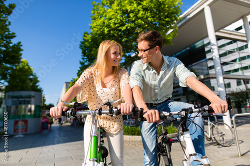 Photo: urban couple riding bike in free time in city urban couple riding bike in free time in city
