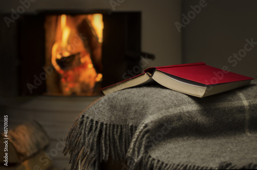 Photo: Peaceful and warm image of a open book by fireplace. Peaceful and warm image of a open book by fireplace.