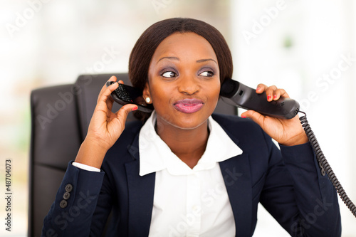 Photo: female african american office worker talking on two phones female african american office worker talking on two phones