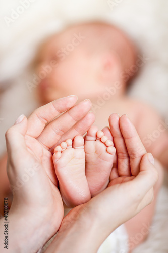 Photo: mother hands holding small baby's feet mother hands holding small baby's feet