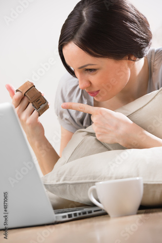 Photo: A young woman lying on the floor in front of her laptop and chat A young woman lying on the floor in front of her laptop and chat