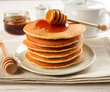 Pancakes with honey on a white table