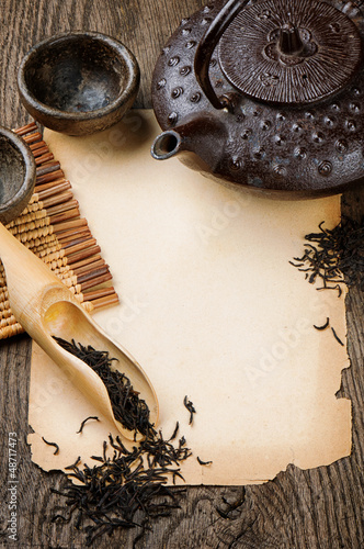 Photo: Frame with Asian teapot, dried black tea and vintage paper Frame with Asian teapot, dried black tea and vintage paper