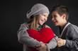 Couple of kids having fun with red heart over black background.