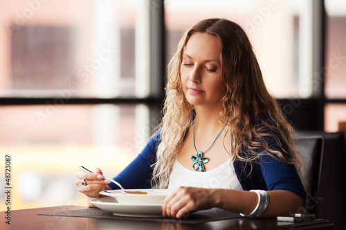 Photo: Beautiful woman eating a soup at restaurant Beautiful woman eating a soup at restaurant