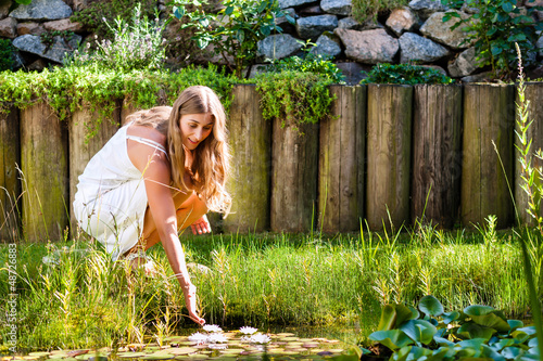 Photo: Woman sitting at pond in her garden Woman sitting at pond in her garden
