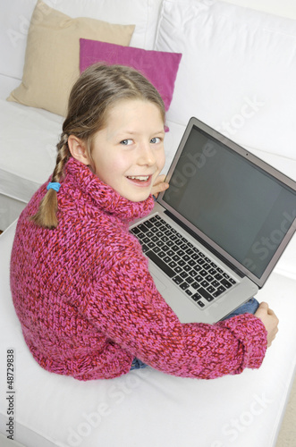 Photo: Mädchen mit Laptop im Schoss blickt in die Kamera Mädchen mit Laptop im Schoss blickt in die Kamera