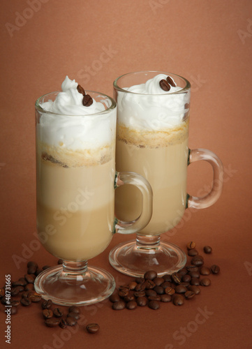 Photo: Fragrant coffee latte in glasses cups, on brown background Fragrant coffee latte in glasses cups, on brown background