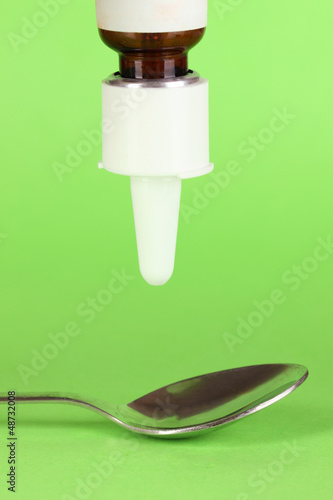 Photo: Medical droplet in spoon on green background Medical droplet in spoon on green background