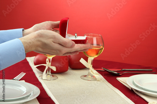 Photo: A man proposing and holding up an engagement ring over A man proposing and holding up an engagement ring over