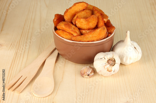 Photo: Appetizing village potatoes in bowl on wooden table close-up Appetizing village potatoes in bowl on wooden table close-up