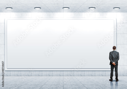 Photo: Business person standing near a blank billboard Business person standing near a blank billboard