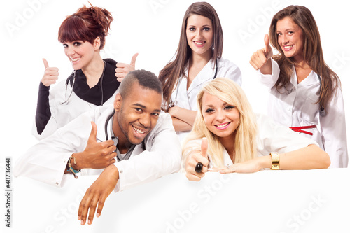 Photo: Young medical students smiling making positive thumb gesture Young medical students smiling making positive thumb gesture
