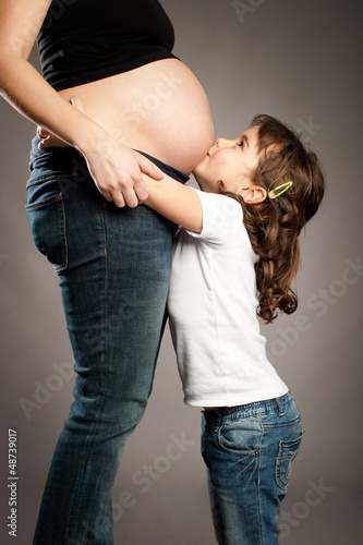 Photo: little girl kissing her pregnant mother little girl kissing her pregnant mother