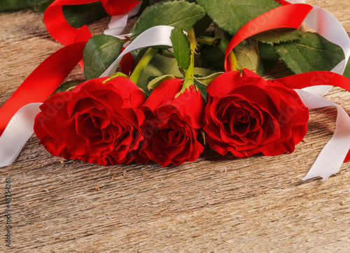 Photo: Red roses on wooden background Red roses on wooden background