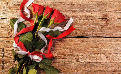 Photo: Red roses on wooden background Red roses on wooden background