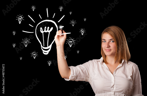 Photo: Woman drawing light bulb on whiteboard Woman drawing light bulb on whiteboard