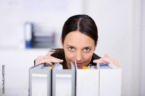 Photo: frau im büro schaut über aktenordner frau im büro schaut über aktenordner