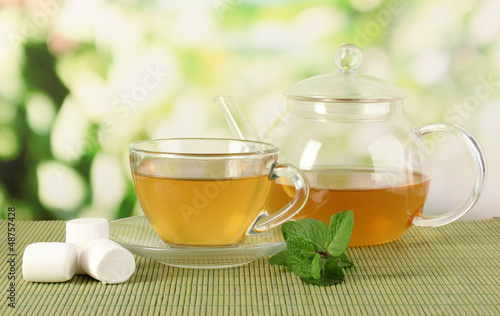 Photo: Cup of tea with mint on table on bright bacground Cup of tea with mint on table on bright bacground