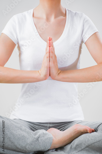 Photo: A young woman sitting in the lotus position while meditating A young woman sitting in the lotus position while meditating