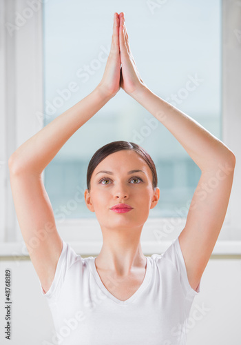 Photo: Portrait of a young beauty performing the yoga sitting tree posi Portrait of a young beauty performing the yoga sitting tree posi