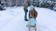 Young parents sledding his child on a park alley