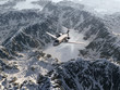 aircraft flies over a snowy mountain range