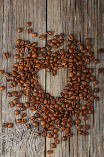 Photo: Heart shape made from coffee beans on wooden table. Heart shape made from coffee beans on wooden table.