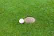 Golf ball on lip on cup