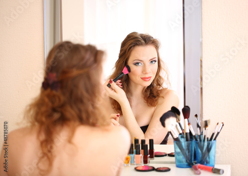 Photo: Young beautiful woman making make-up near mirror Young beautiful woman making make-up near mirror