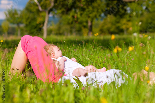 Photo: Mother playing with baby on meadow Mother playing with baby on meadow