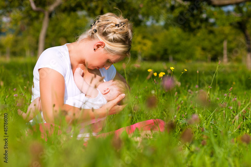 Photo: Mother nursing baby on meadow Mother nursing baby on meadow