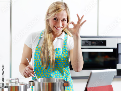 Photo: Woman in home kitchen using electronic tablet for cooking Woman in home kitchen using electronic tablet for cooking