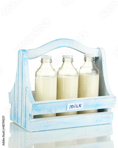 Photo: Milk in bottles in wooden box isolated on white Milk in bottles in wooden box isolated on white